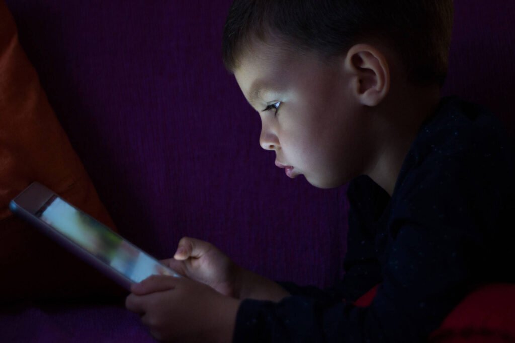 A child looking at a tablet in the dark