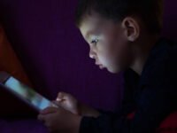 A child looking at a tablet in the dark