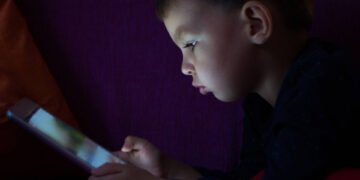 A child looking at a tablet in the dark